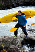Man hikes along river with kayak Bend, Oregon, USA