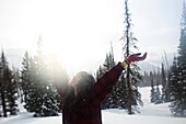 A beautiful women smiles while hiking through a pristine snow field at sunset in Wyoming Bozeman, Montana, USA