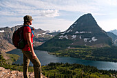 A young female hiker looks out over Hidden Lake and Bear Hat Mountain in Glacier National Park, Montana Glacier National Park, Montana, USA