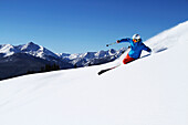 A athletic skier rips fresh powder turns on a sunny day in Colorado Vail, Colorado, USA