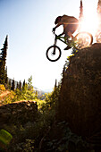 A athletic man mountain biking jumps off a large cliff while downhilling in Wyoming., Jackson, Wyoming, USA
