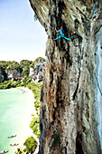 A athletic man rock climbing high above the beach on a multi pitch route in Thailand., Railay, Thailand