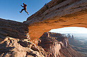 A male jumping off sandstone arch, Canyonlands National Park, Moab, Utah., Moab, Utah, usa