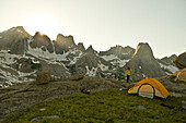 A woman standing next to tent at sunset, Cirque of Towers, Wind River Range, Pinedale, Wyoming., Pinedale, Wyoming, usa