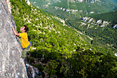 A wide angle perspective on Gerome Pouvreau leading a difficult rock climb on a limestone wall., Millau, France