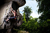 A male climber ascents a protruding rock feature of previously unknown bouldering problem in Hameln, Germany., Hameln, Lower Saxony, Germany