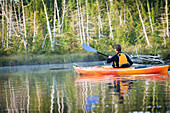 Rear view of a woman kayaking on Spencer Pond, Maine., Maine, USA