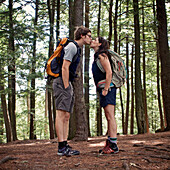 A young couple kisses while hiking in a forest., Ashfield, MA, USA