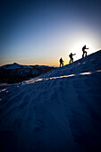 Three backcountry skiers silhouetted in beautiful sunrise light., South Lake Tahoe, California, USA