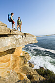 Hikers on edge of rocky ocean cliff Sydney, New South Wales, Australia