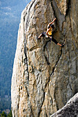 Attractive woman rock climbing high above a valley floor South Lake Tahoe, California, United States