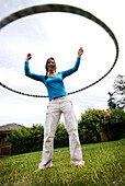 A young woman hula hoops on a green lawn in British Columbia, Canada British Columbia, USA