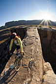 Mountain biker crossing sandstone bridge, Canyonlands, Utah Moab, Utah, USA