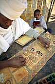 Priester Sine Tebeb malt und beschreibt biblische Szenen in Geez auf Ziegenhäute, bei Bet Giyorgis, St.-Georgs-Kirche, Lalibela, Amhara, Äthiopien
