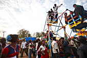 People in a manual small ferris wheel, Angadehalli Belur, Karnataka, India
