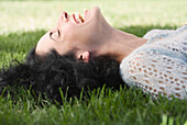 Young woman laying on grass, Unknown