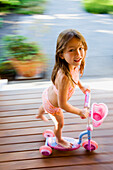Asian girl riding foot powered scooter, Seattle, WA