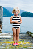 Young girl in bathing suit standing on wooden pier, Bellingham, WA