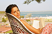 Young woman reading outdoors, Cape Cod, MA