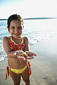 Hispanic girl holding starfish, Morrocoy, Venezuela