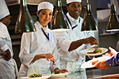 Multi-ethnic chefs garnishing plates of food, Orlando, FL