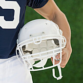 Hispanic male football player holding helmet, Studio