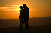Hispanic couple kissing outdoors at sunset, Seattle, WA