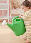 Mixed race baby girl holding watering can, Jersey City, NJ