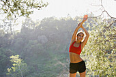 Hispanic woman stretching arms overhead, Los Angeles, CA