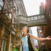 Mixed race woman with arms outstretched on urban street