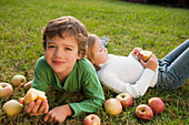 Mixed race brother and sister laying in grass with apples, Virginia Beach, VA