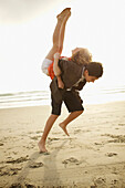 Boy lifting girl on back on beach, Coronado, CA
