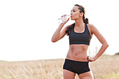 Serious mixed race woman in sportswear drinking water, Seattle, WA, USA