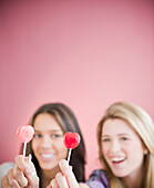 Teenage girls holding heart-shape lollipops, Jersey City, New Jersey, USA