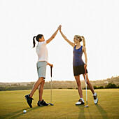 Women golfers high fiving on golf course, Mission Viejo, California, USA