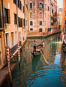 Gondolier rowing gondola in canal, Venice, Venezia, Italy