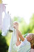 Caucasian mother and baby hanging laundry on clothes line, St Louis, Missouri, United States