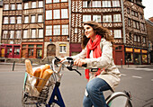 Caucasian woman riding bicycle with bread in basket, Rennes, Brittany, France