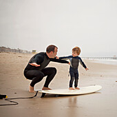 Caucasian father teaching son to surf, Manhattan Beach, California, USA