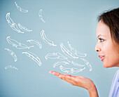 Cape Verdean woman blowing illustrations of feathers, Jersey City, New Jersey, USA