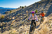 Couple mountain biking down hill, Taos, New Mexico, USA