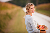 Caucasian woman picking fruit on rural road, Cape Charles, VA, USA