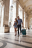 Caucasian couple pulling luggage in city, Turin, Piedmont, Italy