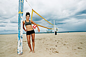 Gemischtrassige Frau hält Volleyball am Strand, Redondo Beach, Kalifornien, USA