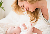 Caucasian mother and baby laying on bed, Jersey City, New Jersey, USA