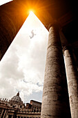 Sun rising over columned buildings, Roma, Vaticano, Italy