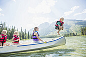 Caucasian boy jumping from canoe into lake, Jackson, Wyoming, USA
