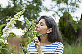 Hispanic woman smelling flowers in garden, Santa Fe, New Mexico, USA