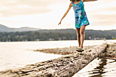 Mixed race girl walking on log, Bellingham, Washington, USA