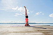 Weiße Frau übt Yoga auf einem hölzernen Steg, Seattle, WA, USA